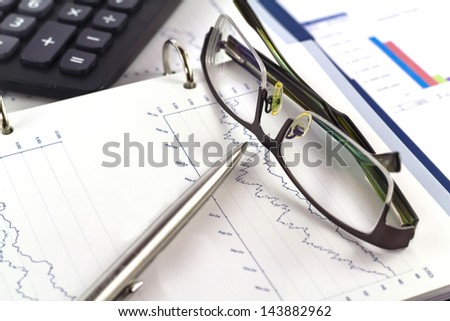 Business finance report with graphs and glasses , pen