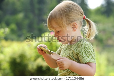 A three year old girl plays with her mother\'s powder compact