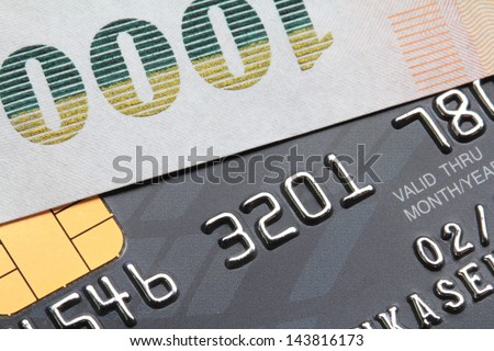Bank note laid on a black credit card