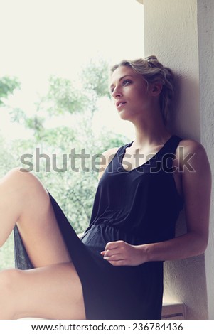 Young woman sitting by golden light in holiday villa.