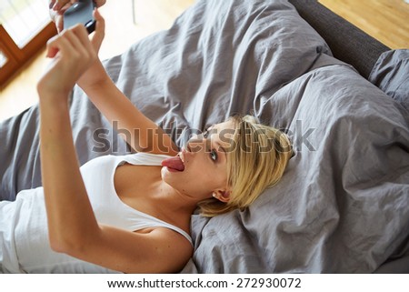 sexy young woman lying on the bed and make a selfie