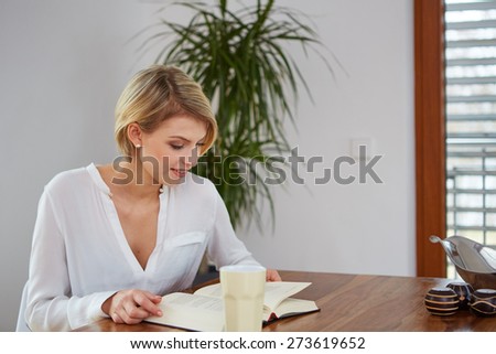 Beautiful woman reading a book at a table