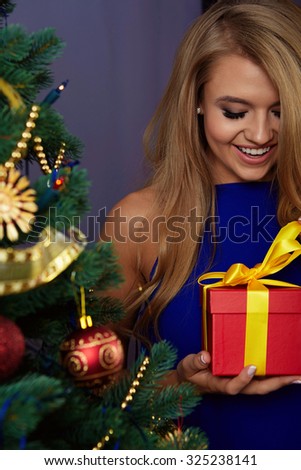 young pretty woman under new year tree with christmas present