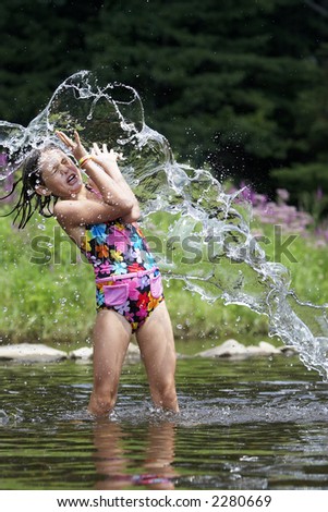 A young girl getting a big splash of water on a hot summer day