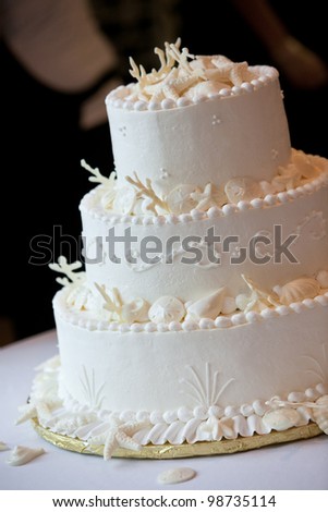 a white ocean themed wedding cake with miniature seashell design and details