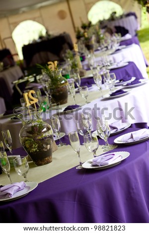 Wedding tables set up for fine dining in Green and Purple, unique centerpieces.