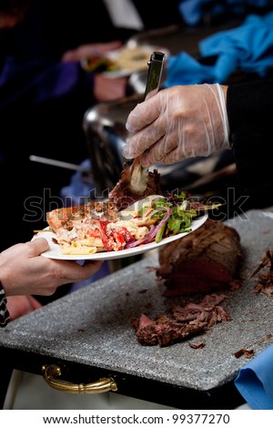 a gloved hand serving wedding food at a catered event