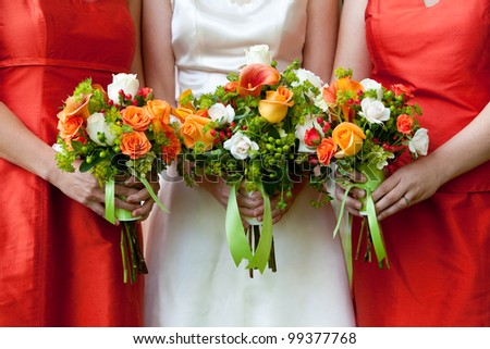 three wedding bouquets being held by a bride and her bridesmaids