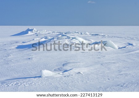Ice and snow on a sunny sea, ocean. Continuous, unbroken winter white sea in bright sunshine.