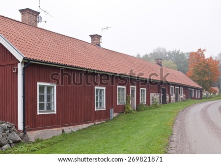 Red wooden building along a gravel road. Environment in earth tune colors.