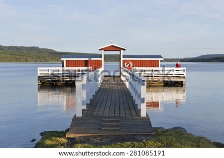 GREAT-LAKE, SWEDEN ON JULY 03. Unidentified people fishing from a bridge on July 03, 2012 by the Great-Lake, Sweden. Red and white wooden bridge, forest and ridges in the background.