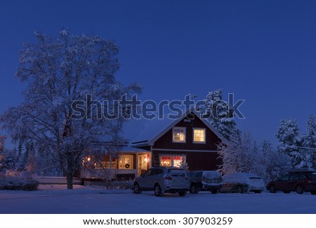 LAPLAND, SWEDEN ON DECEMBER 24. Winter house and vehicles in the night on December 24, 2014 in Lapland, Sweden.  Farm buildings after sunset up North on Christmas Eve, cars this side.