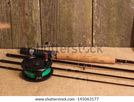 Fly fishing gear on burlap against cedar wood wall