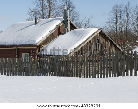 View of small wooden country house under snow on winter sunny day