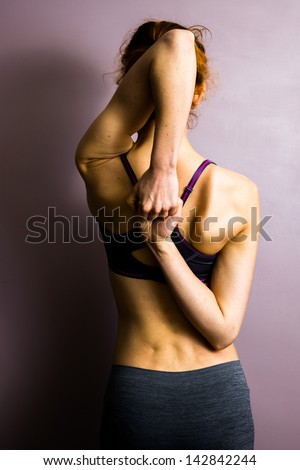 Young woman doing yoga and stretching her arms and shoulders
