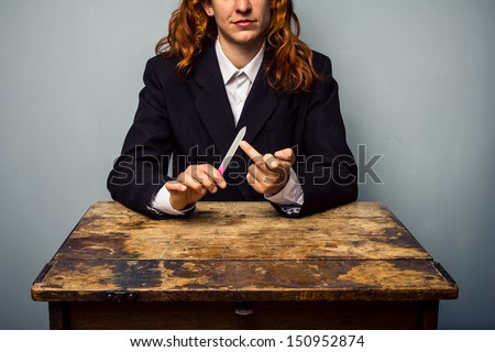 Businesswoman displaying obscene gesture while filing her nails