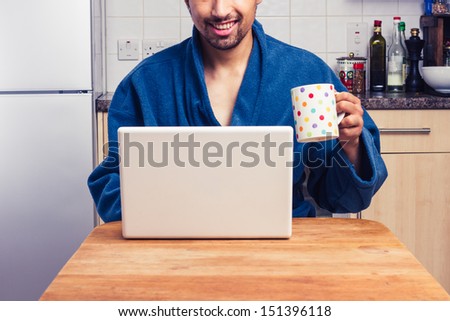 Man in robe checking emails and having coffee