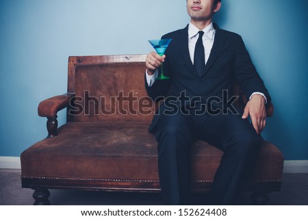 Businessman on vintage sofa drinking cocktail