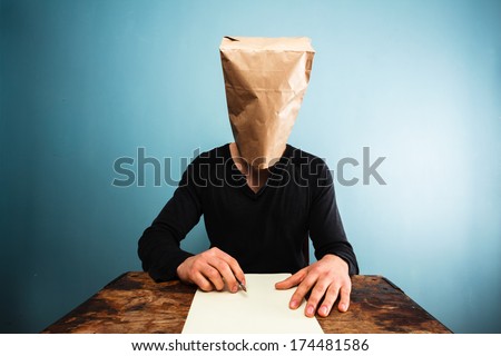 Man with bag over head writing letter