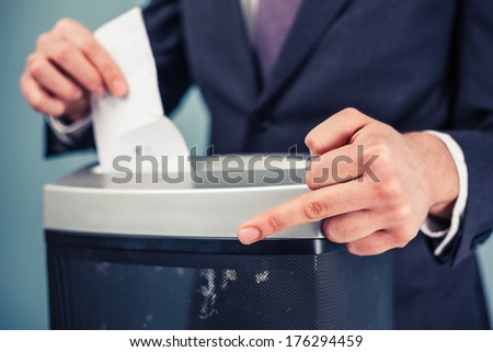 A white collar criminal is displaying obscene gesture while destroying evidence in shredder