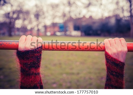 Closeup on a young woman\'s hands as she is hanging from a monkey bar in the park