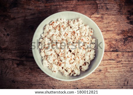 A large bowl of popcorn on a wooden table