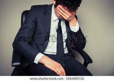 Sad and tired businessman is sitting in an office chair