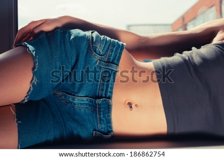 Young woman with a flat stomach is lying on the window sill