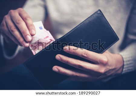 Closeup on a man\'s hands as he is getting a banknote out of his wallet