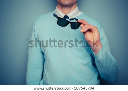 A smartly dressed young man with a pair of sunglasses