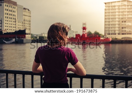A young woman is relaxing by a river and looking at a dereclict building across it Zdjęcia stock © 