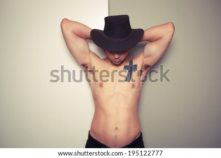 Sexy shirtless young cowboy posing against a green and white background