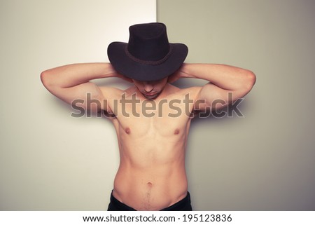 Sexy shirtless young cowboy posing against a green and white background