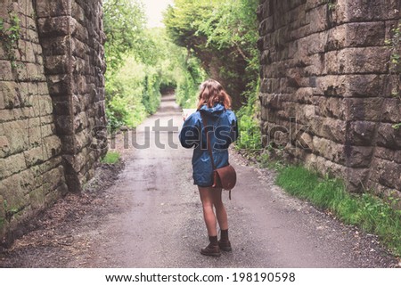 A young woman is lost in a forest below a railway bridge and is studying a map