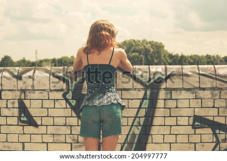 A young woman is looking over a wall outside