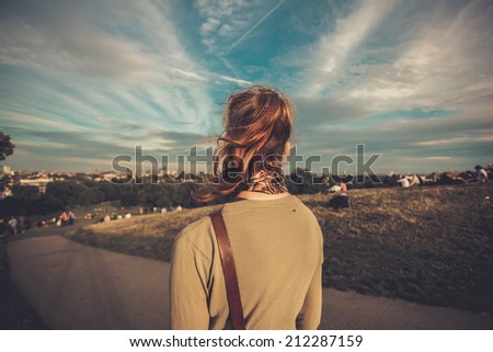 A young woman is admiring the city view from a hill in the park