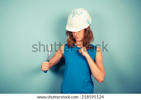 A young female builder is holding a chisel in an aggresive manner