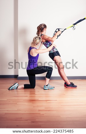 An athletic young woman is working out and is being corrected by her personal trainer