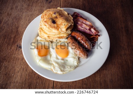A breakfast with short stack of pancakes, bacon, eggs and sausage