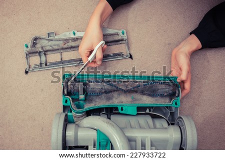 A woman\'s hands are cleaning and repairing a vacuum cleaner