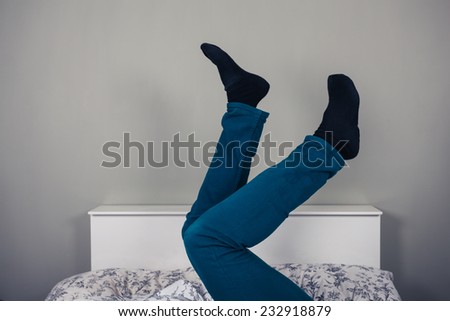A man is lying in a bed with his legs raised