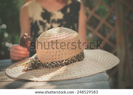 A young woman is sitting at a table with a big straw hat in front of her