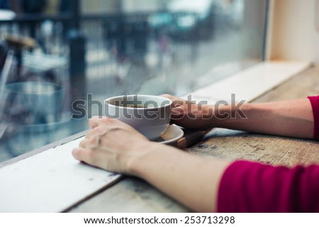 A young woman is having a coffee by the window in a cafe