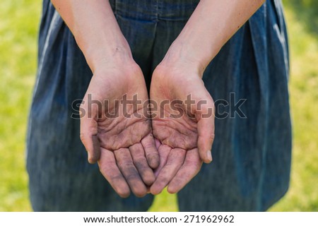 A young woman is showing of her dirty hands covered in dirt from gardening