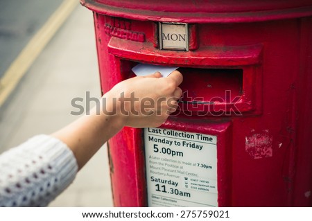 2 May 2015, London, United Kingdom - A female hand is posting a letter in a mail box belonging to Royal Mail