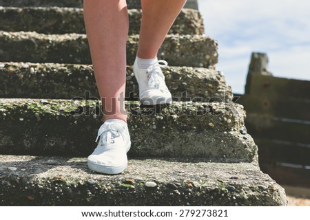 The bare legs of a young woman as she is walking down some steps on the beach