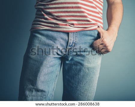A very sexy young man is posing with one hand in his pocket