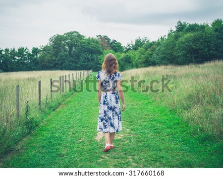 A young woman is walking in the countryside on a gloomy day