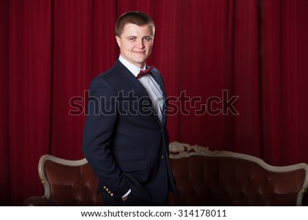 Happy young man in jacket and bowtie expressing positivity