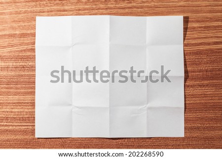 Folded white paper on a wooden floor.